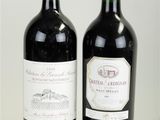 two bottles of red wine sitting next to each other on a white surface