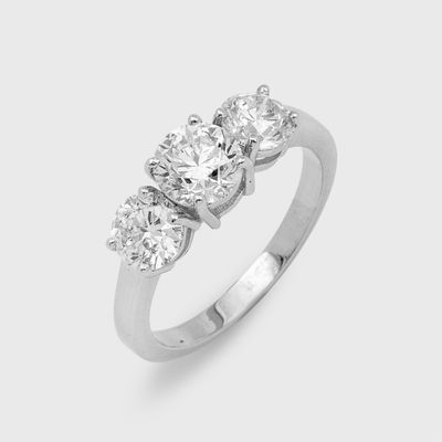 a close up of a three stone diamond ring on a white background