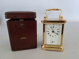 a small clock sitting next to a box on a table