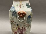 a vase with a handle that has a picture of people on it