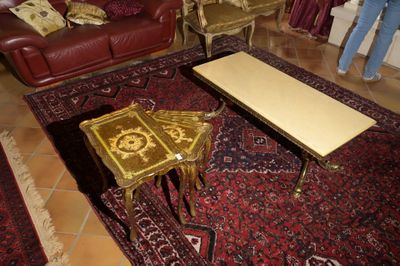 Une personne se tient dans un salon où se trouvent un tapis et une table basse.