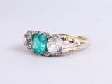 a close up of a gold ring with an emerald and white topaz