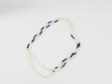 un collier de perles blanches et bleues posé sur un fond blanc