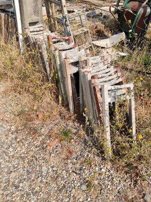 a pile of old wooden chairs sitting on the side of the road