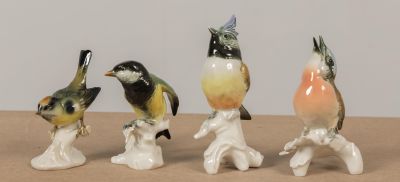 quatre figurines d'oiseaux posées sur une table en bois
