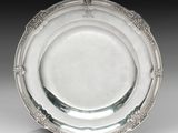 une assiette en argent antique avec un motif décoratif sur le bord