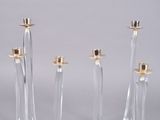 trois bougeoirs en verre transparent surmontés de bougeoirs dorés