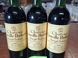trois bouteilles de vin posées sur une table, à côté d'une étiquette de prix