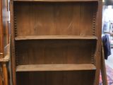 une bibliothèque en bois dont la porte est ouverte, dans une pièce