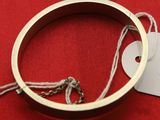 un bracelet auquel est attachée une étiquette, posé sur un fond rouge