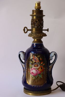 une lampe en forme de vase bleu, avec un socle doré et un motif floral