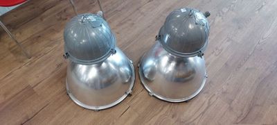deux lampes en métal posées sur un parquet, à côté d'une chaise rouge