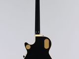 a black and gold guitar hanging from a white wall