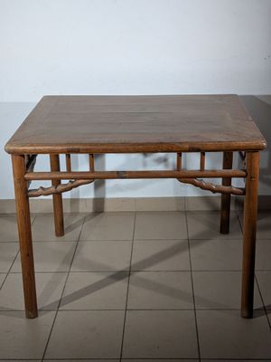 a wooden table with a brown top on a tiled floor