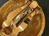 a close up of a gold brooch on a black surface