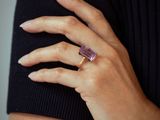 the woman is wearing a ring with a purple stone on it