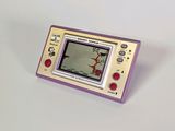 une petite Game Boy violette posée sur une surface blanche