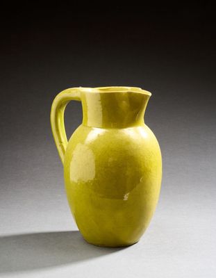 un vase jaune posé sur une surface grise, avec une ombre au sol