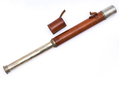 un vieux télescope avec un étui en cuir et une poignée en bois, posé sur une surface blanche