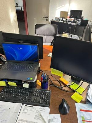 un bureau sur lequel se trouvent un ordinateur portable, un écran, un clavier, une souris et d'autres objets