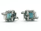 a pair of silver and green stone earrings on a white surface
