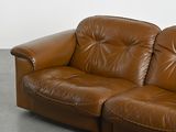 a brown leather couch that is sitting on a concrete floor