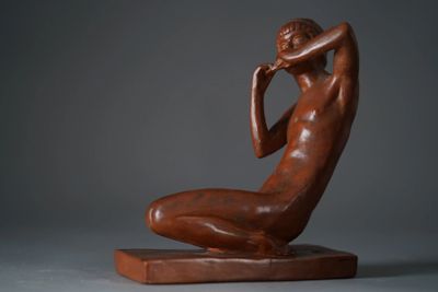 statue of a woman sitting on a wooden base with her hands on her face