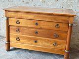 une petite commode en bois posée sur un sol en briques