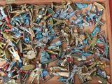 une boîte en bois remplie de figurines de jouets diverses, posée sur un fond rouge