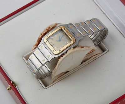 a silver and gold watch sitting in a red box