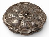 an antique silver plate with a flower design on it on a white surface