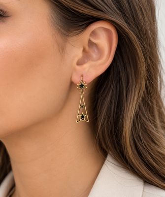 une femme vêtue d'une chemise blanche et portant des boucles d'oreilles en or