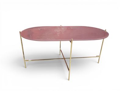 une table basse ovale rose aux pieds dorés sur fond blanc
