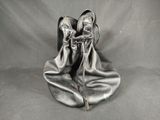 pair of silver leather shoes sitting on top of a gray cloth
