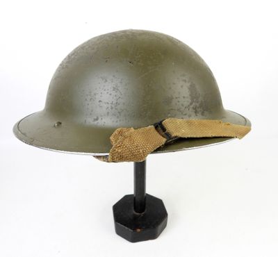 un vieux casque militaire muni d'un bandeau en tissu, posé sur un support