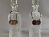pair of clear glass bottles with a gold label and a chain around the neck