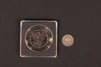 a close up of a coin and a small coin on a black surface