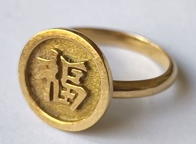une bague en or sur laquelle est gravé un caractère chinois