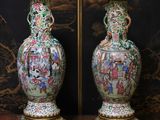 une paire de vases orientaux posés sur un socle devant un papier peint oriental