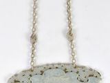 un gros plan d'un collier suspendu à une chaîne sur une surface blanche