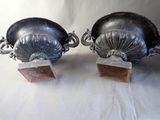 two metal urns with handles on a white surface