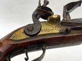 un vieux pistolet avec une crosse plaquée laiton sur fond blanc