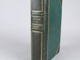 an old book with a green cover sitting on a table