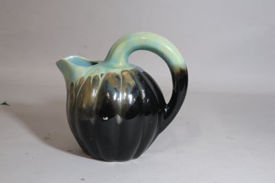 a black and green vase sitting on a white surface