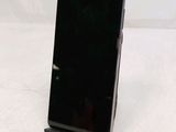 a black cell phone sitting on a stand on a white surface