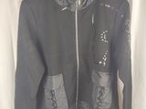 hooded jacket with zippers and pockets on a hanger in front of a white curtain