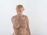 a statue of a woman sitting on a table next to a vase