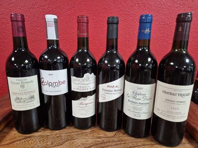 six bottles of red wine are lined up on a wooden barrel