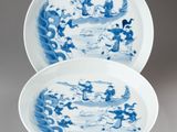 pair of blue and white plates with dragon designs on them