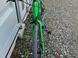 un vélo vert garé à côté d'un immeuble